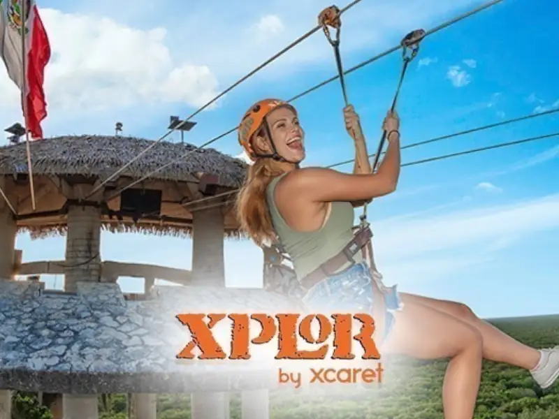 Excursão Xplor Aventura - Mulher a sorrir enquanto desliza numa tirolesa sobre a selva no parque Xplor