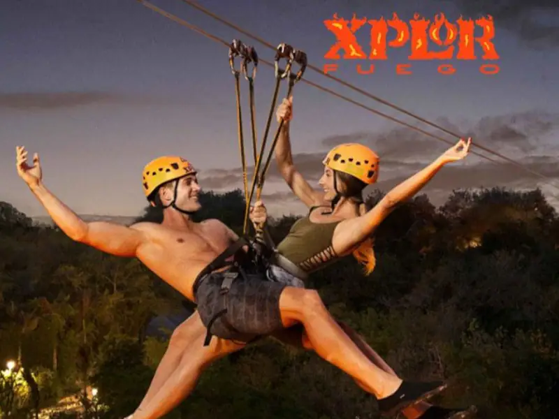 Excursão Xplor Fuego - Casal a deslizar numa tirolesa noturna iluminada por tochas